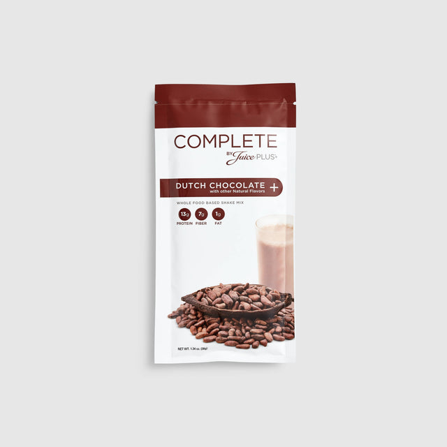 A sachet of Juice Plus+ Complete Dutch Chocolate flavor, showing the product name, an image of chocolate chips, and a prepared chocolate drink.